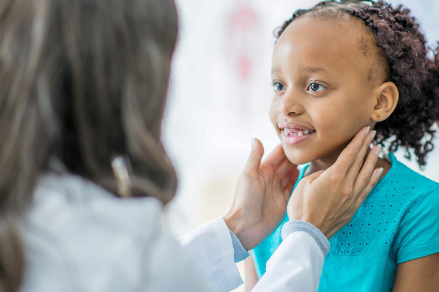Pediatrics-Tonsil-Infection-exam Otolaryngologist examining a young patient's neck for signs of tonsil infection.